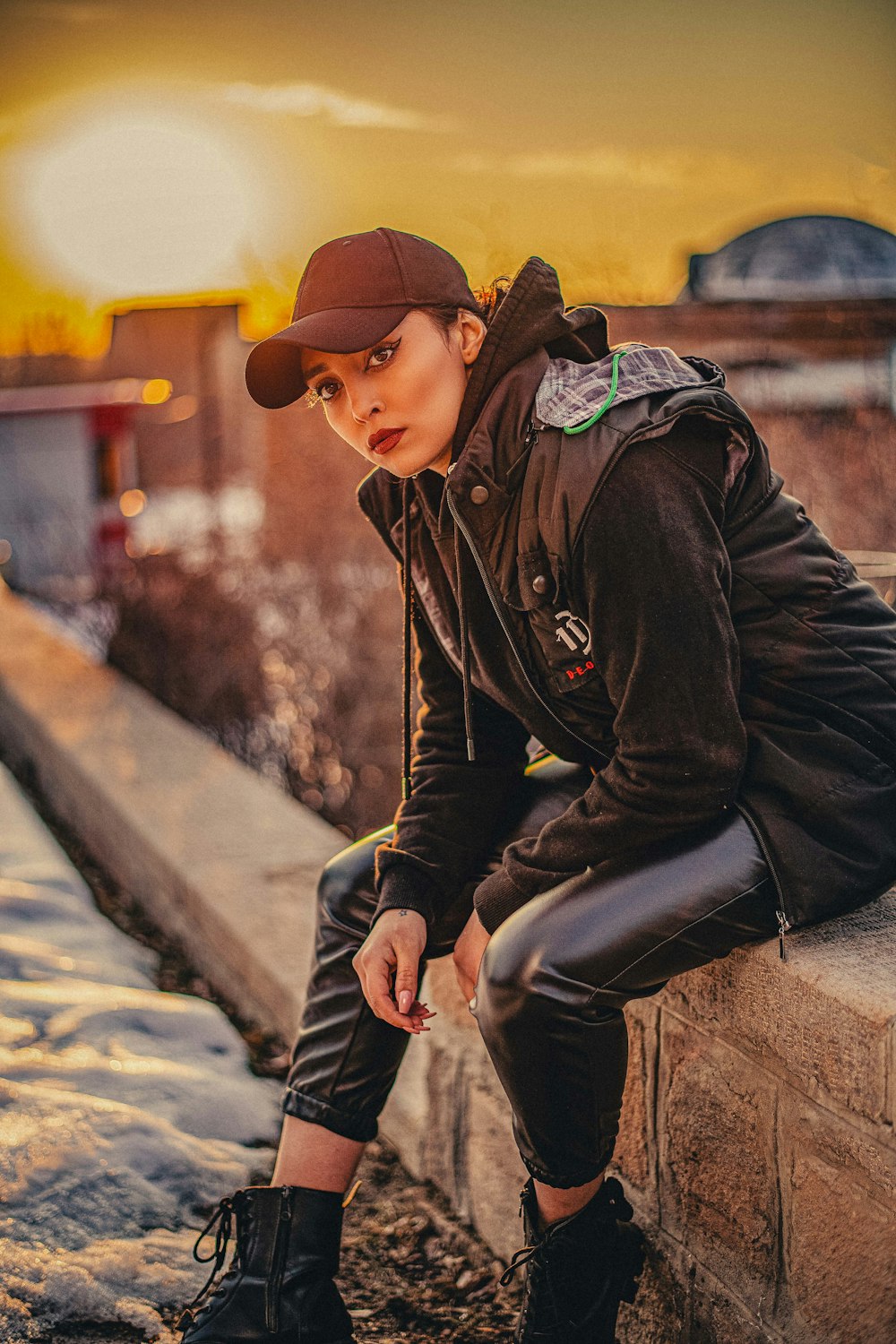 a woman sitting on a ledge with a hat on