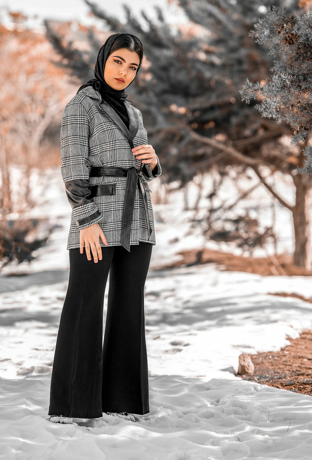 a woman standing in the snow wearing a coat