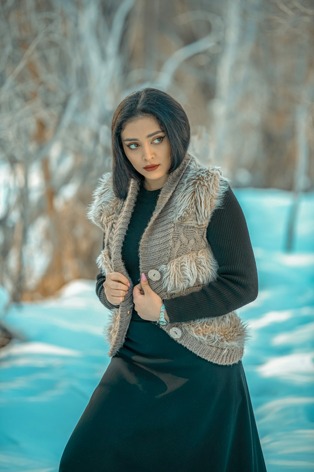 a woman standing in the snow wearing a fur vest