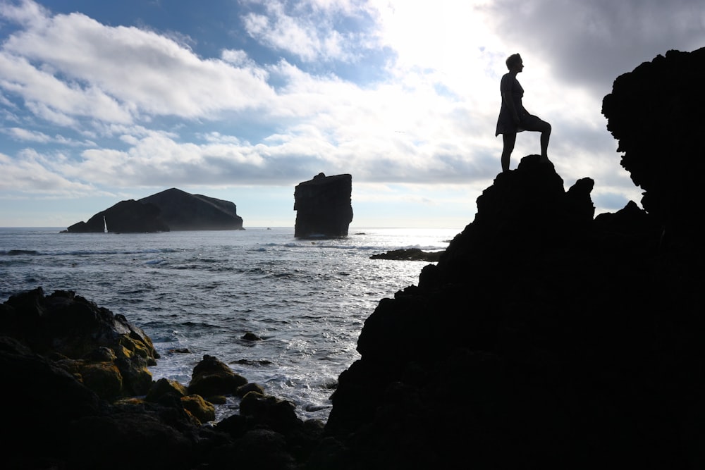 a person standing on a rock near the ocean