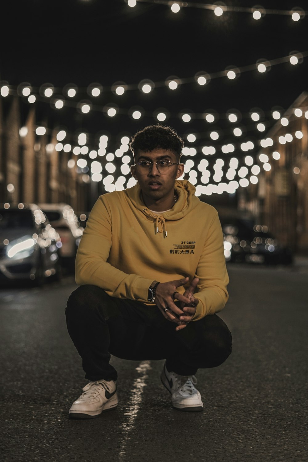 a man in a yellow hoodie squatting on a street
