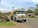 A delivery truck parked in front of a rural home with a propane tank in the yard.