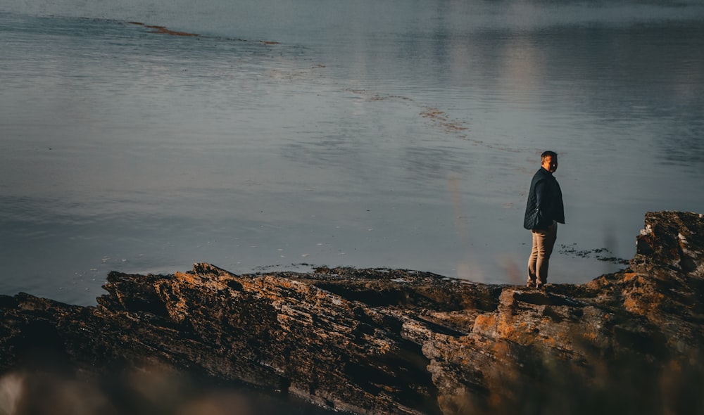 a man standing on the edge of a cliff overlooking a body of water