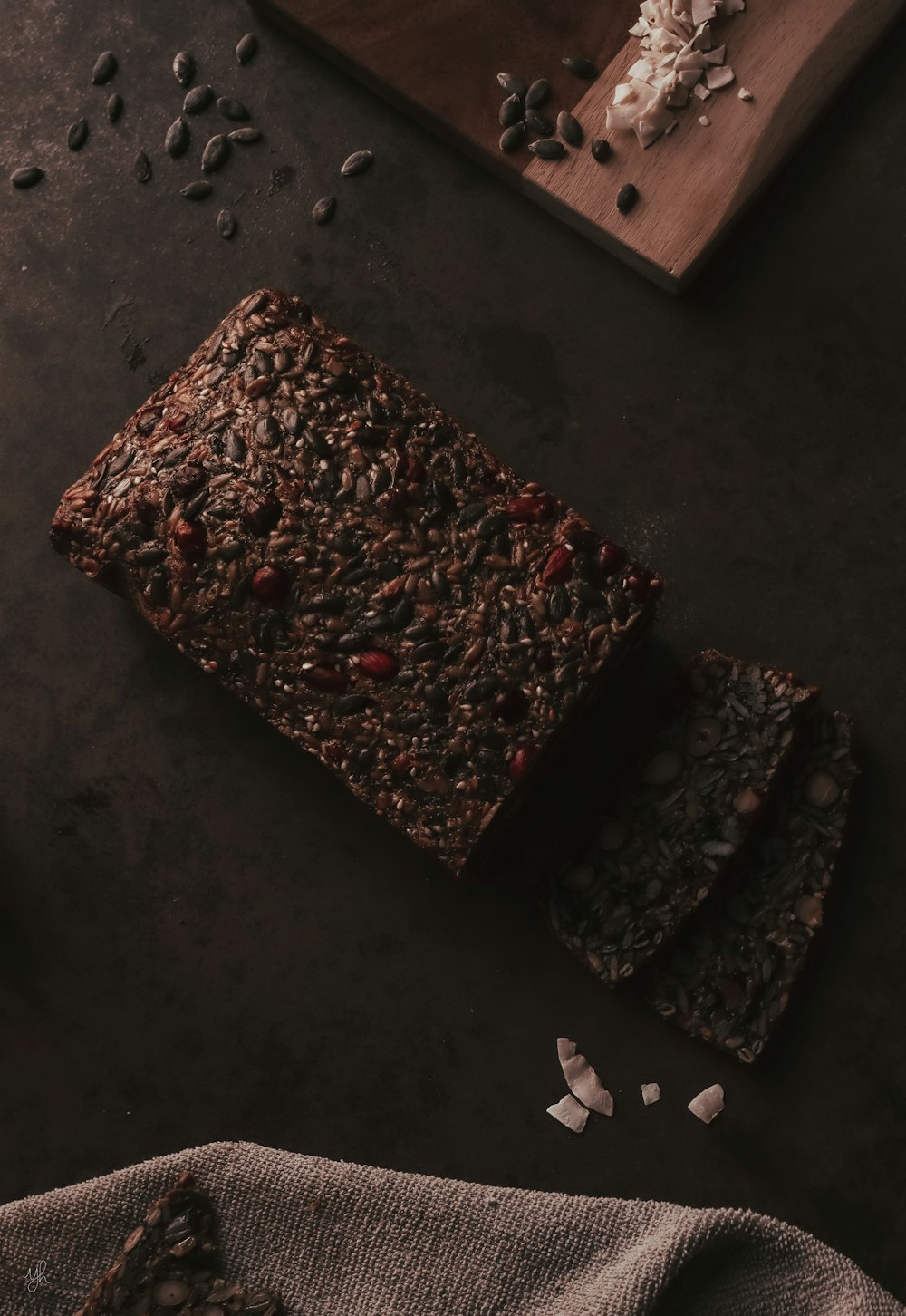 a loaf of chocolate granola bread on a cutting board