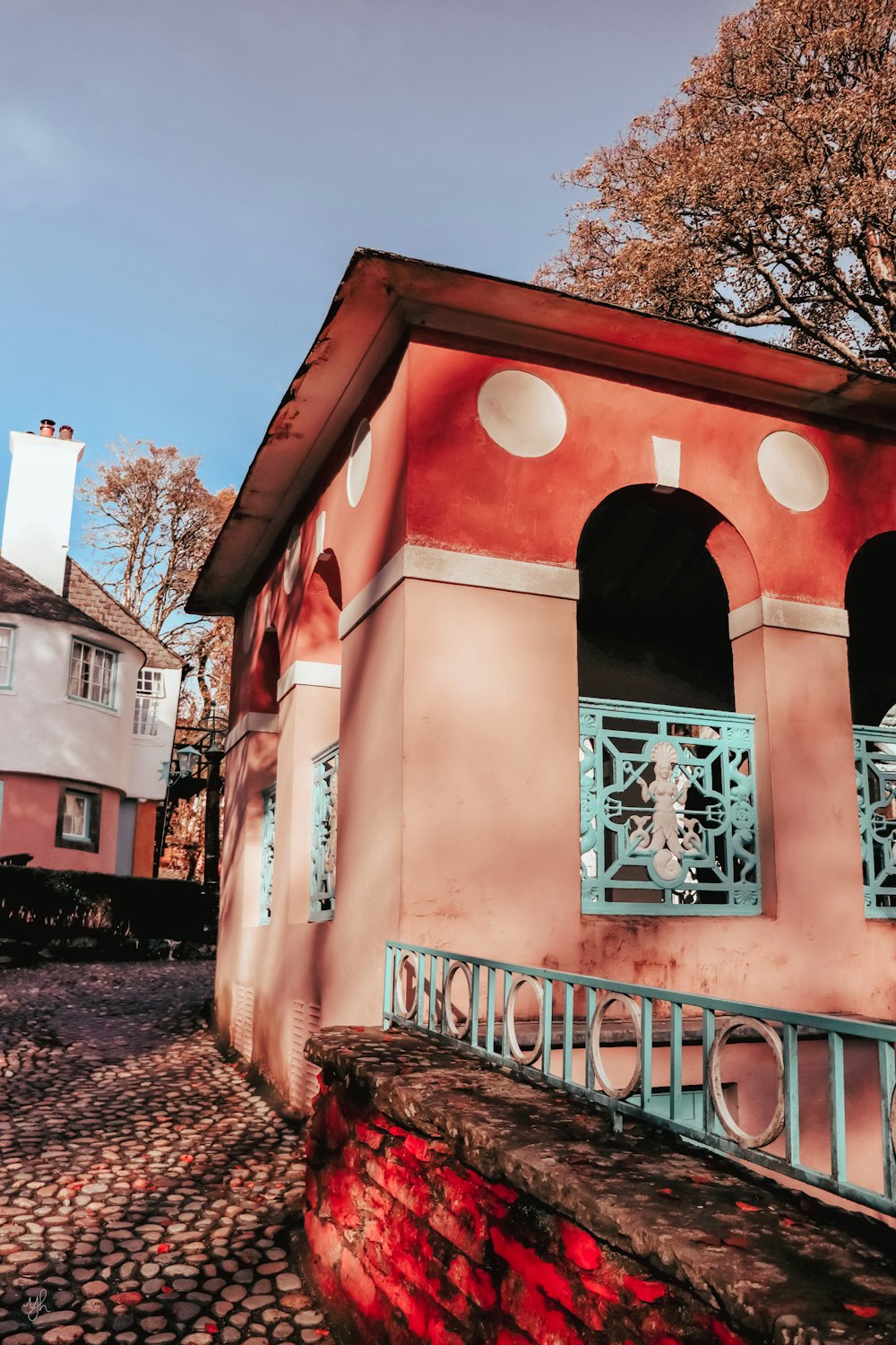 a pink building with a blue window and a red wall