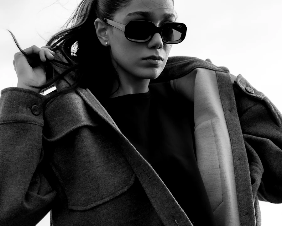 Black and white portrait of a model in a coat and sunglasses