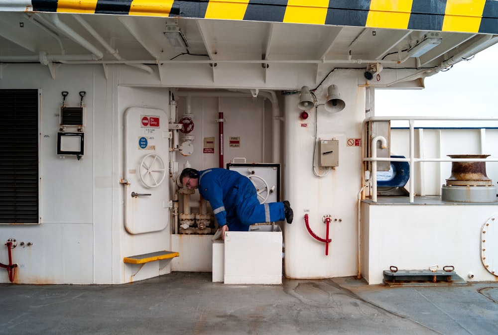 a man in a blue coverall working on a boat
