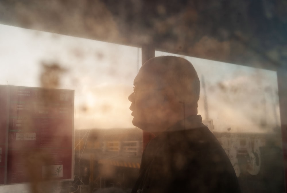 um homem em pé na frente de uma janela ao lado de um sinal