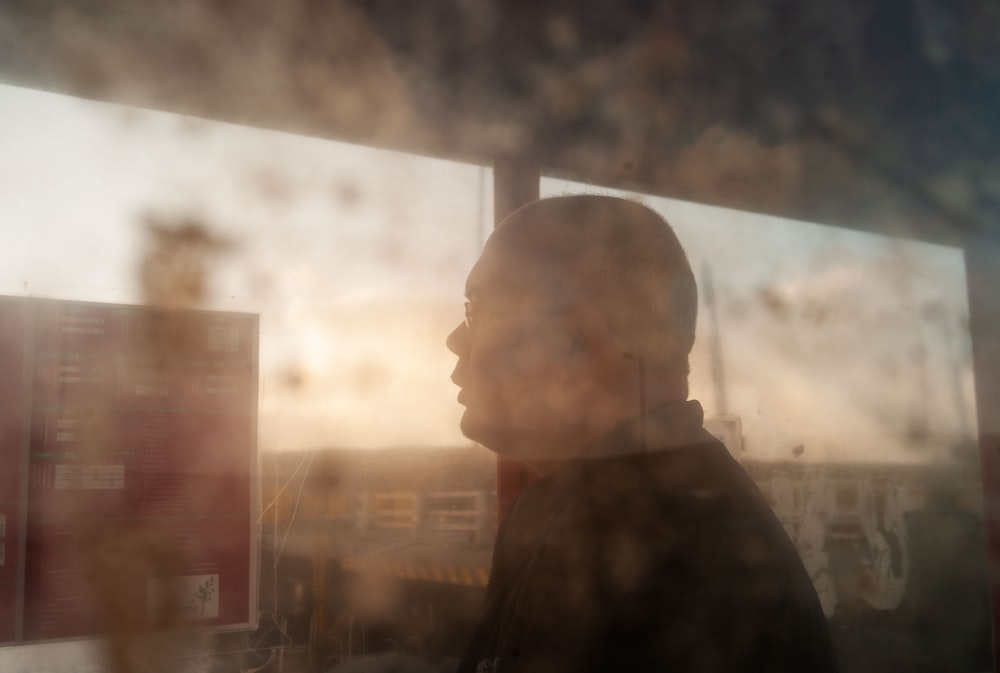 a man standing in front of a window next to a sign