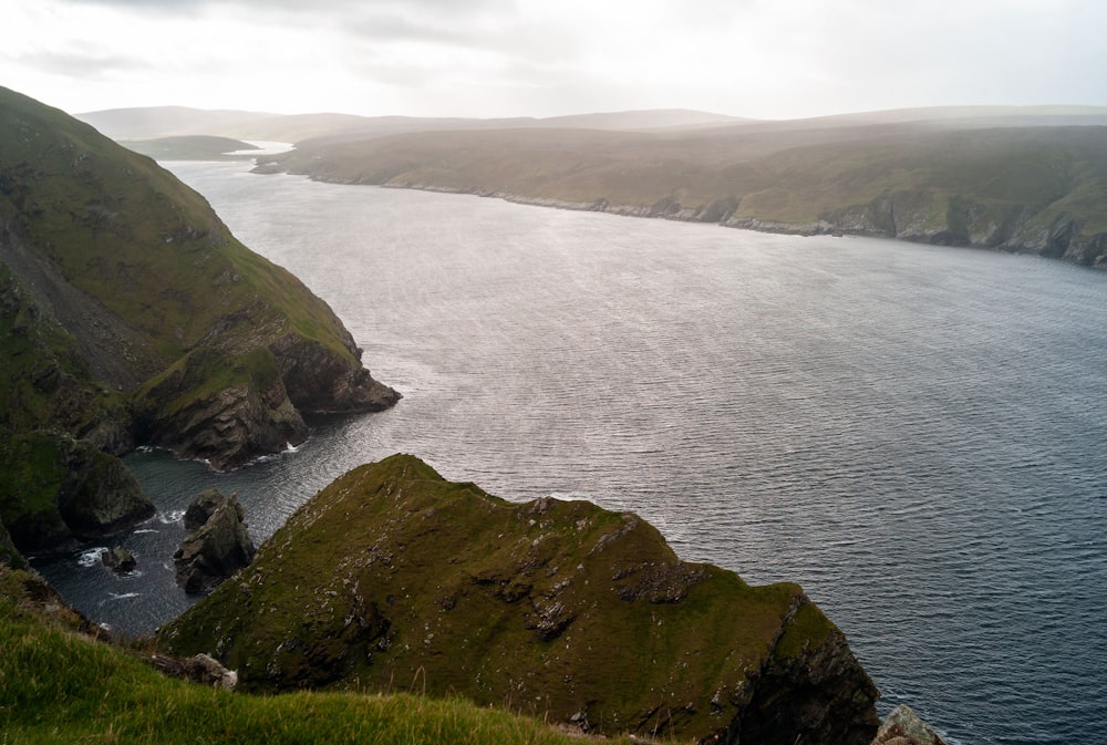 a large body of water surrounded by green hills