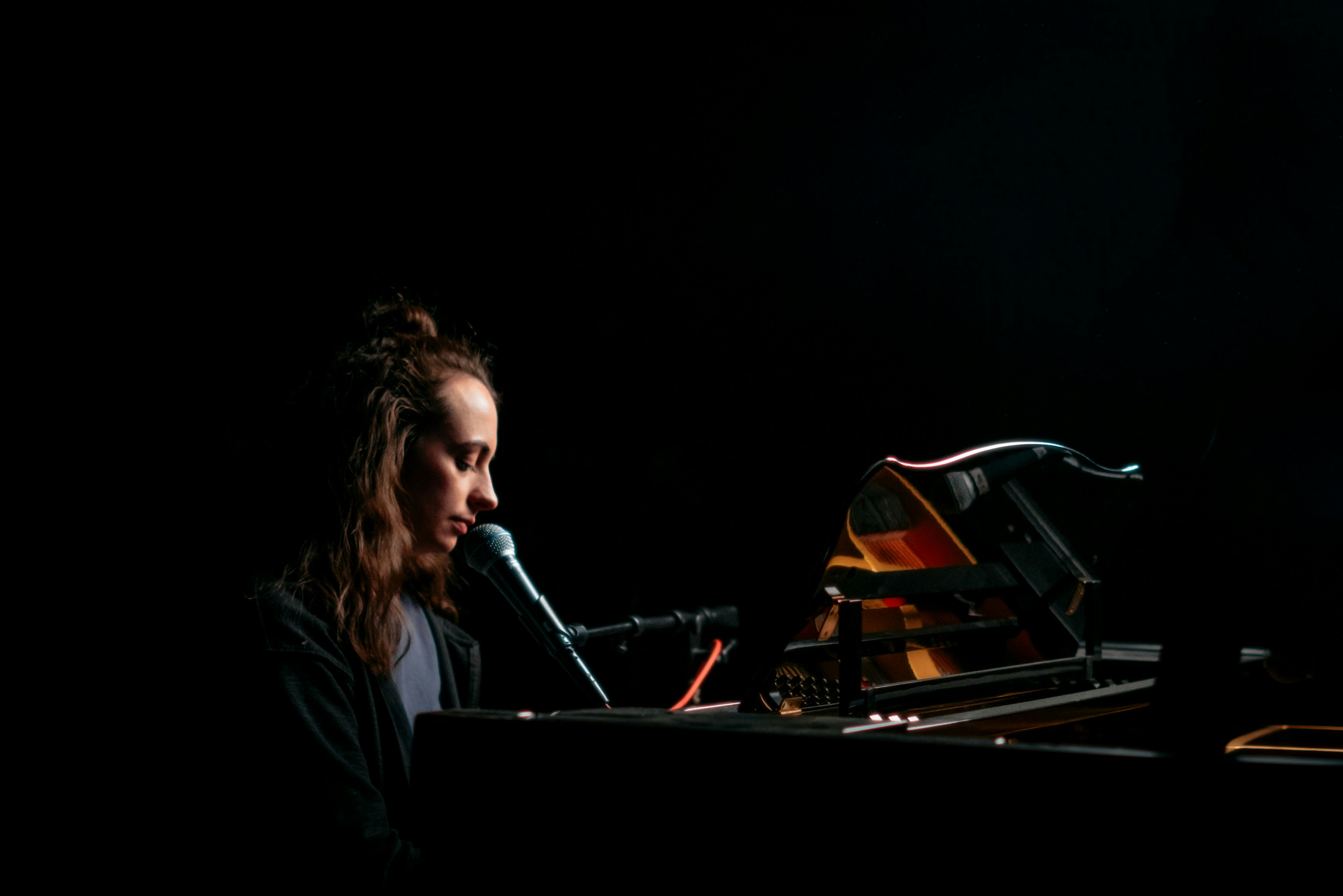a woman sitting at a piano with a microphone