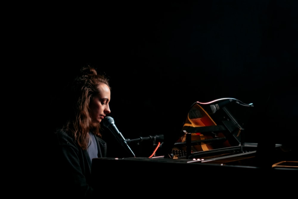a woman sitting at a piano with a microphone