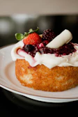 Close-up of a minimalist modern cake with delicate berry decorations on a clean white plate.