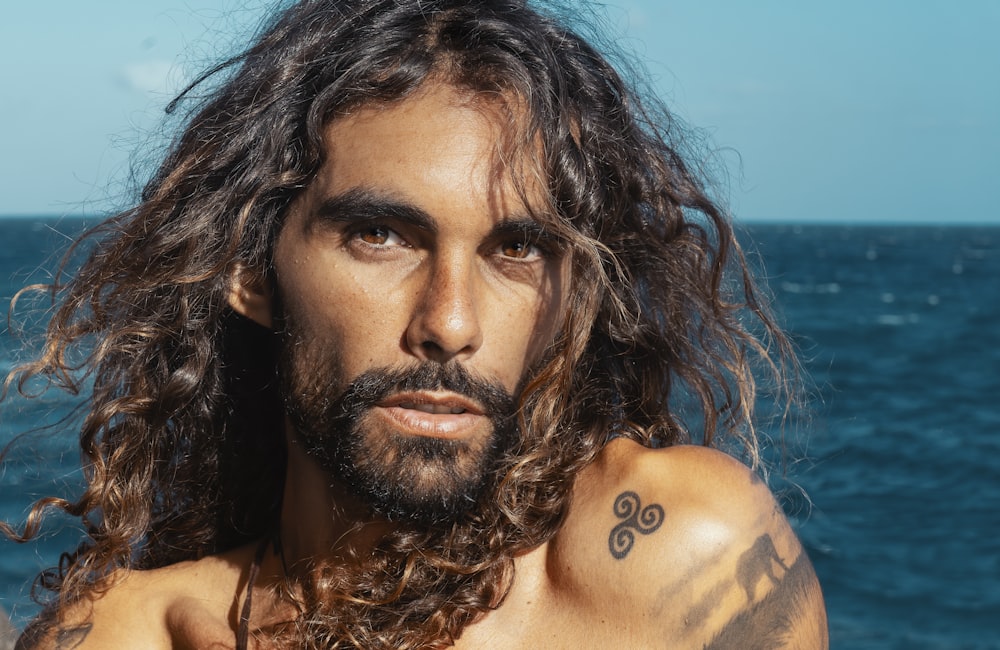 a man with long hair and a tattoo on his arm