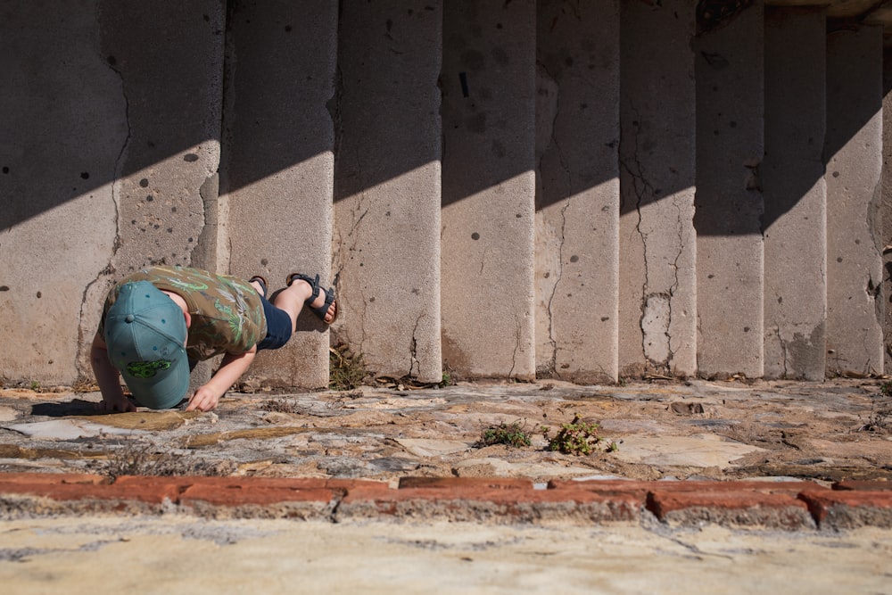 a person kneeling on the ground in front of a wall