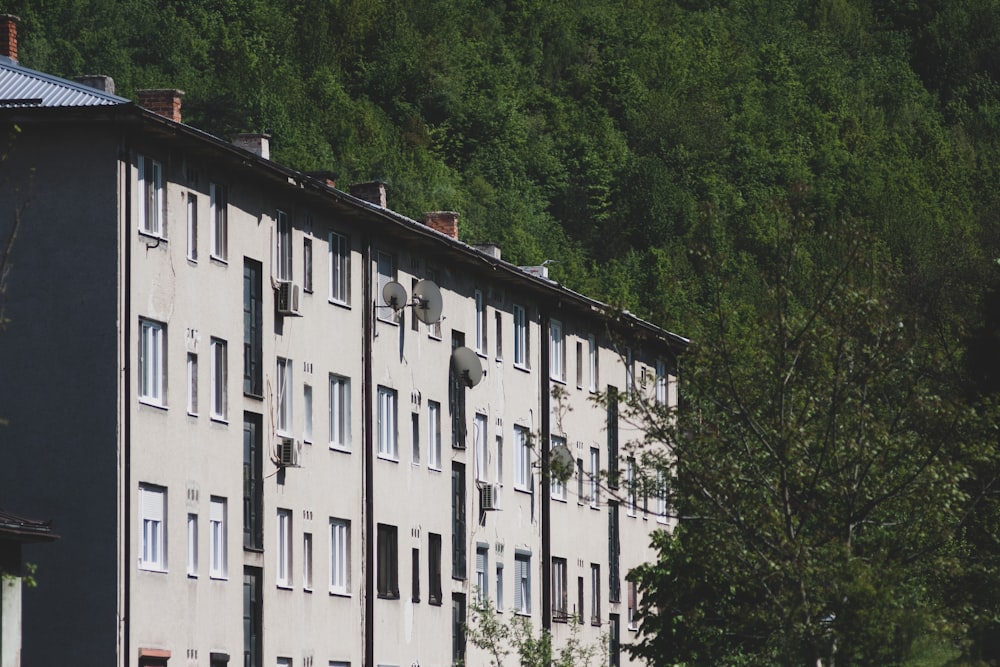 a tall building sitting next to a lush green forest