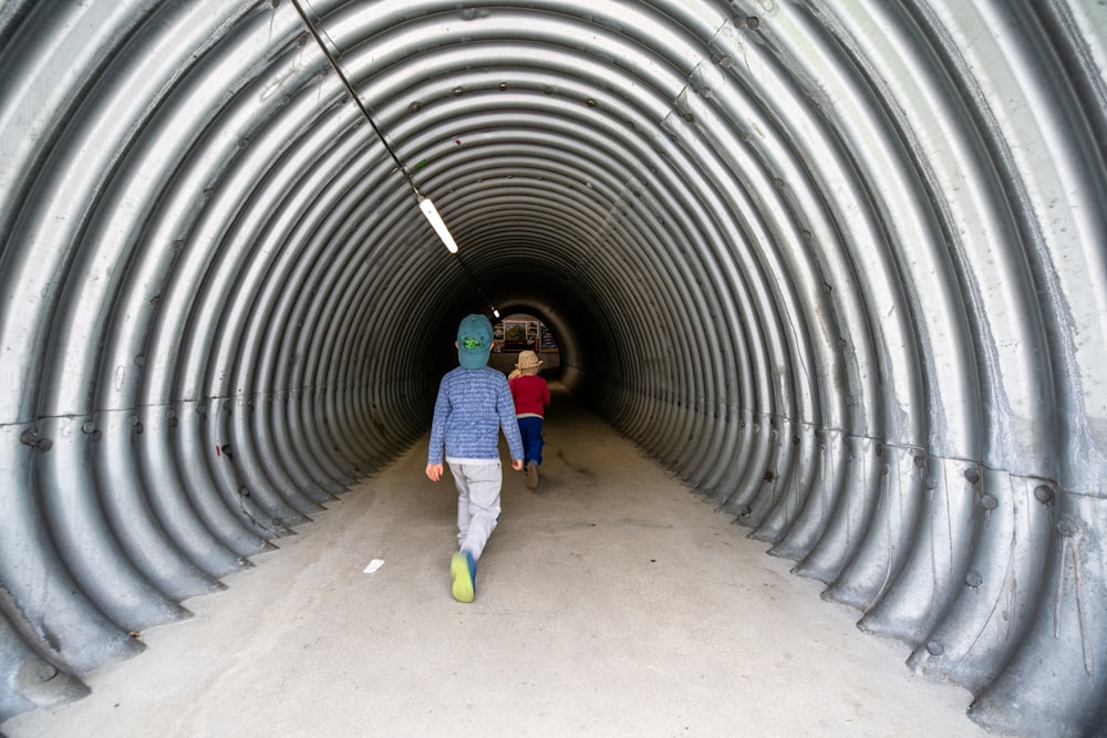 a couple of people that are walking down a tunnel