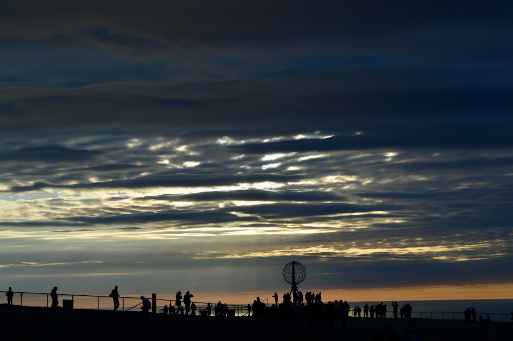 a group of people standing on top of a beach under a cloudy sky