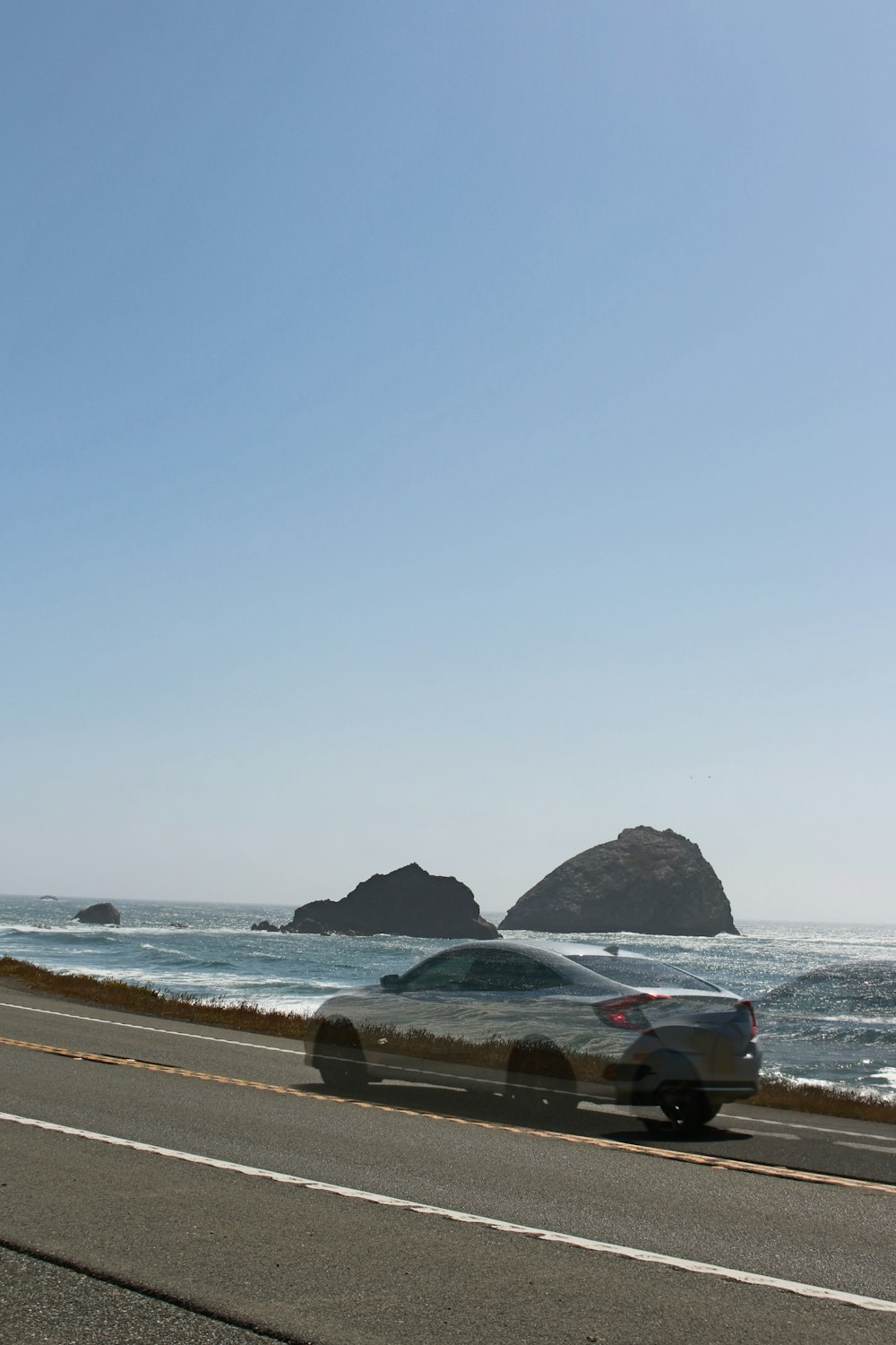 a car driving down a road next to the ocean