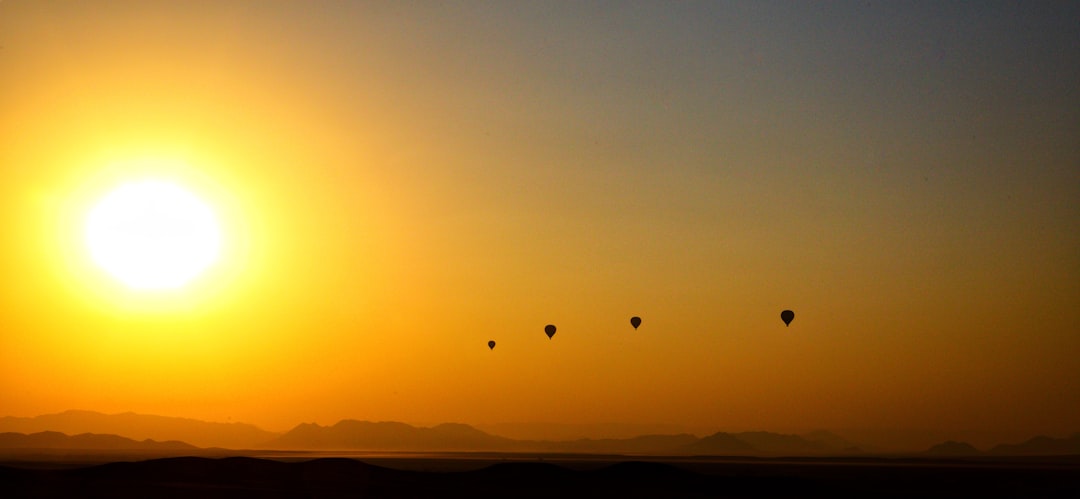 a group of hot air balloons flying in the sky, Hot air balloons at sunrise above Sossusvlei
