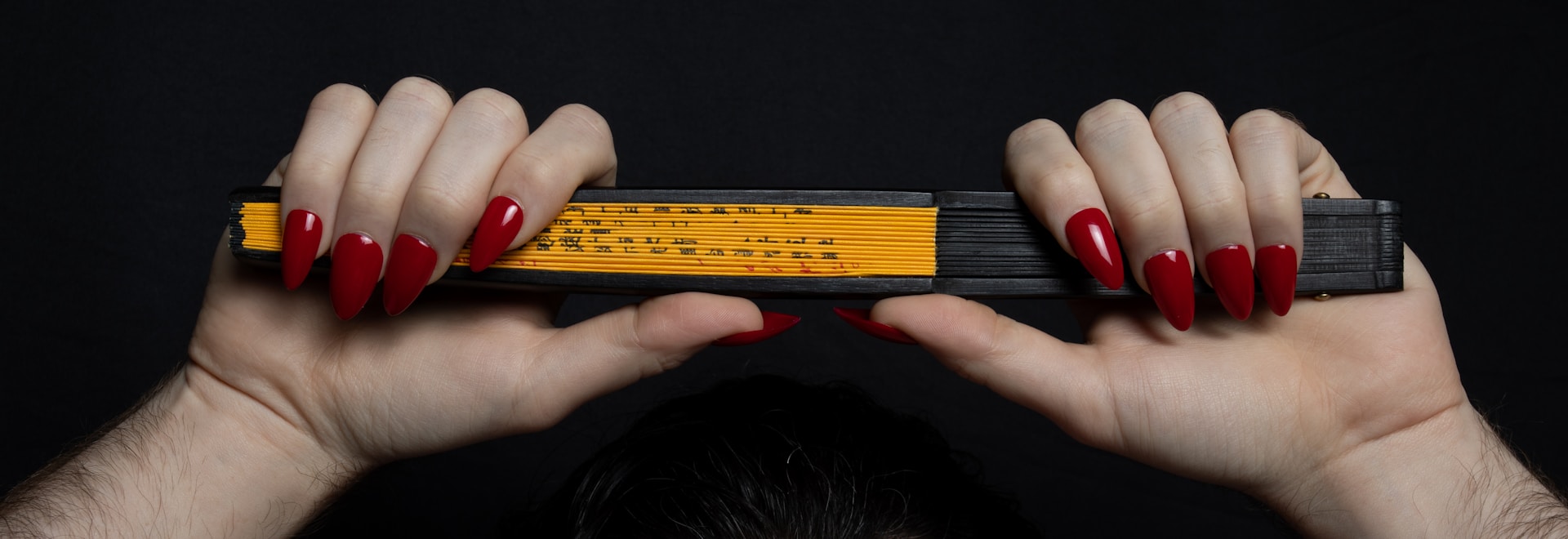 a woman with red nails holding a pencil in front of her face