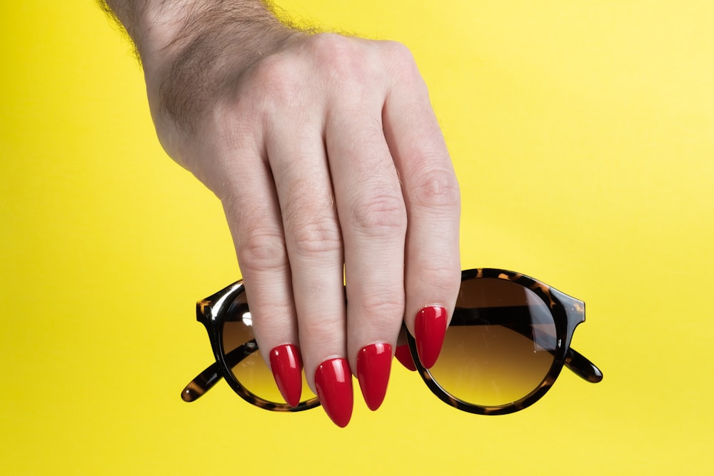 a woman's hand holding onto a pair of sunglasses