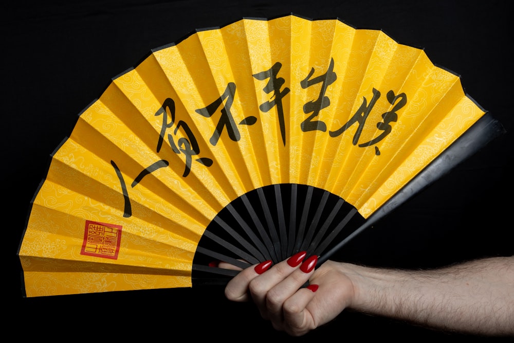 a person holding a yellow fan with writing on it