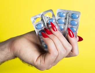 a woman's hand holding two contraptions in front of a yellow background