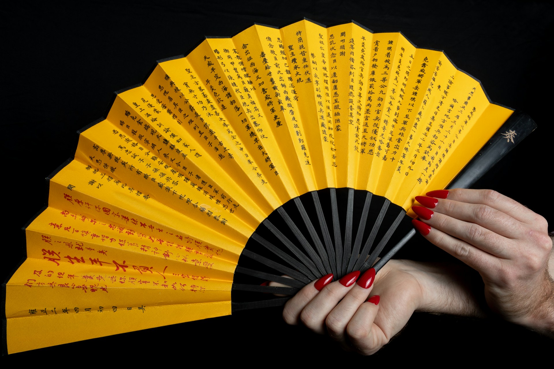 a woman holding a yellow and black fan