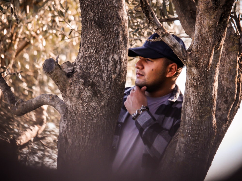 a man standing next to a tree in a forest