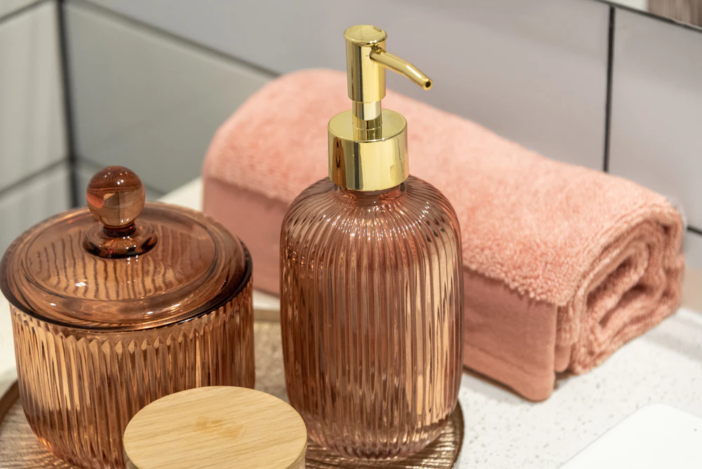 An amber soap dispenser beside a folded pink towel