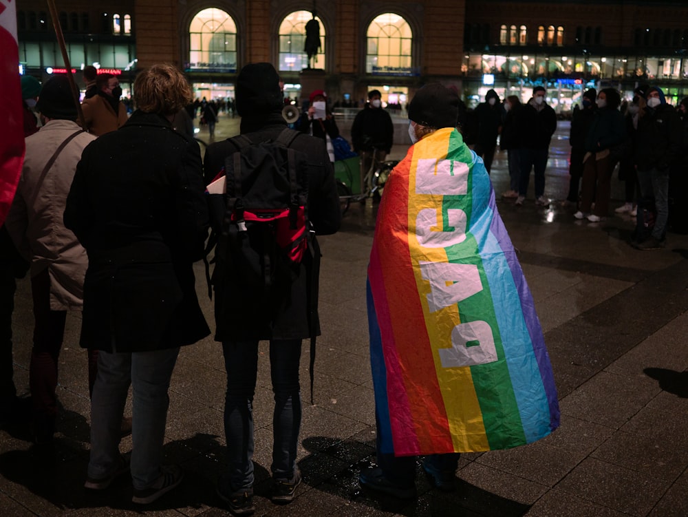 a group of people standing next to each other holding a rainbow flag