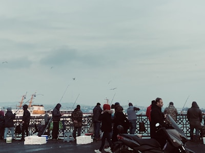 Group of friends wearing Fish Gear Apparel hoodies, gathered on a dock with fishing rods.