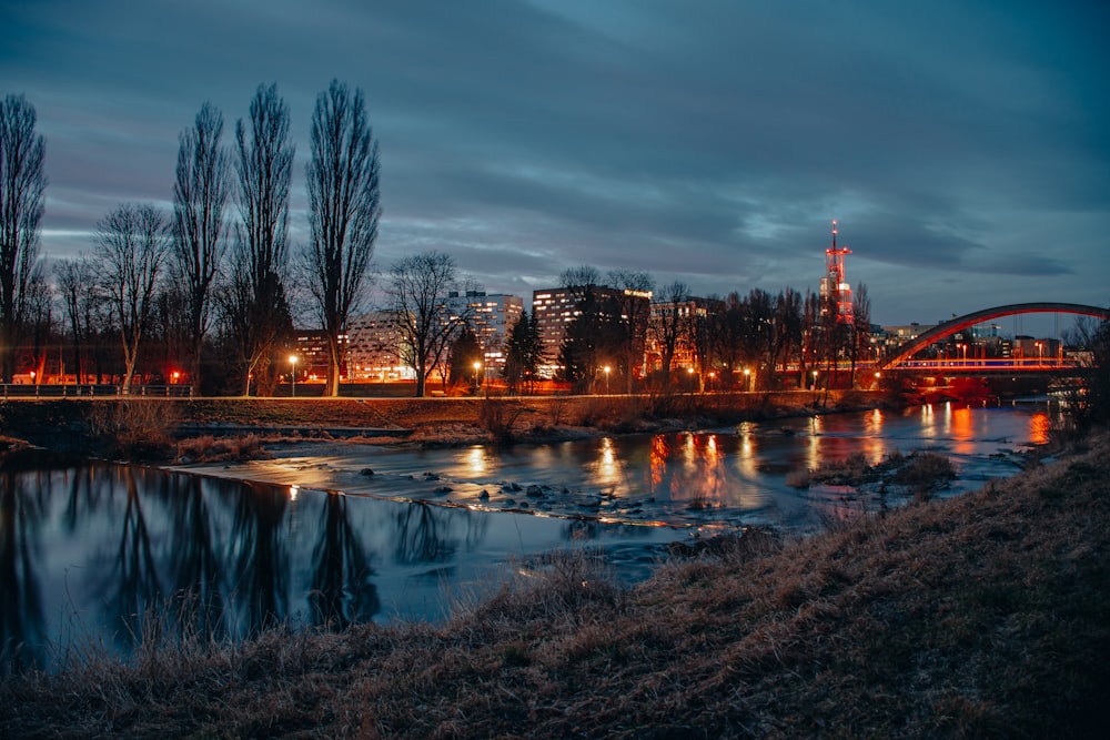 a river with a bridge in the background at night