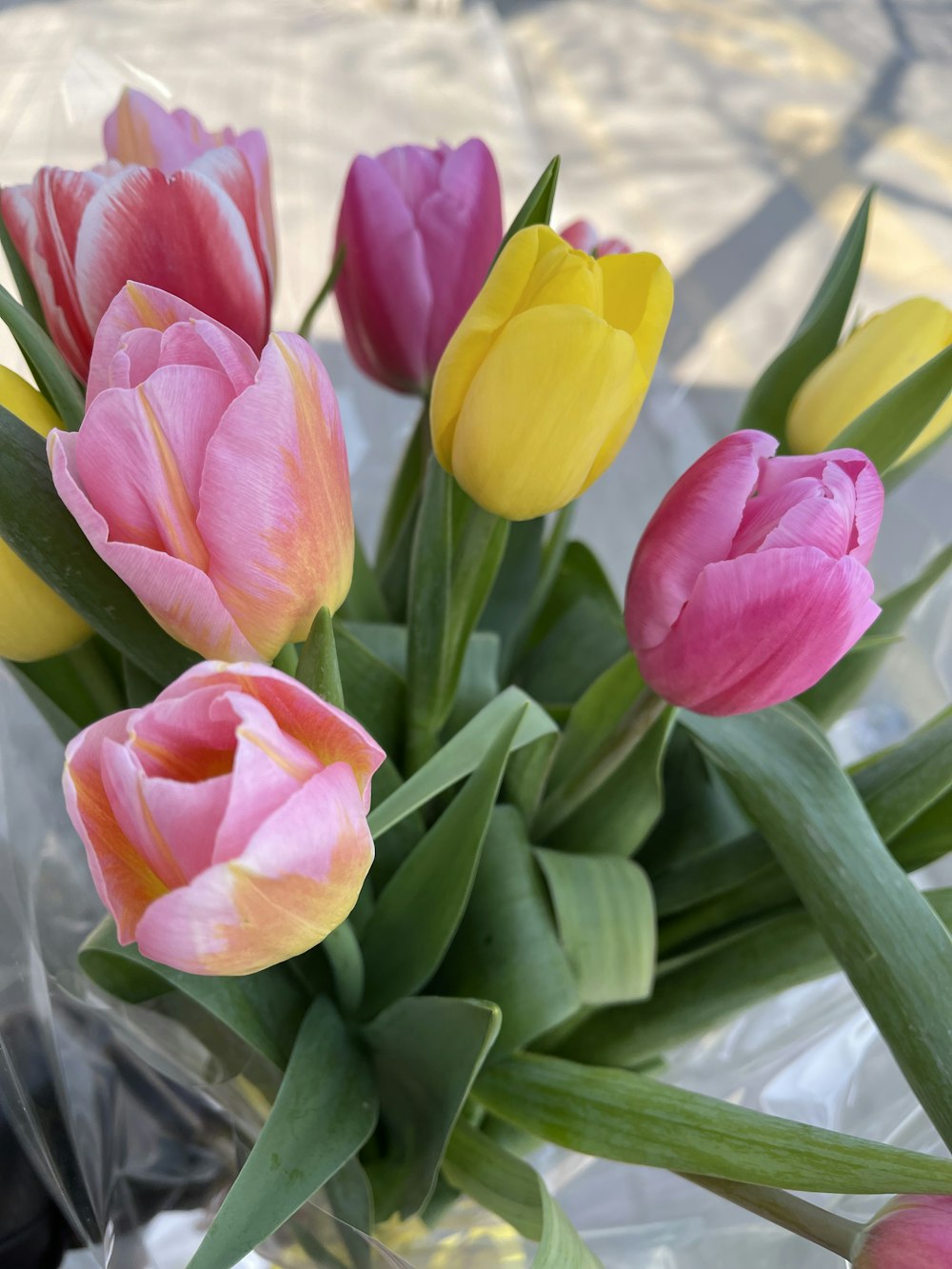 a bunch of pink and yellow tulips in a vase