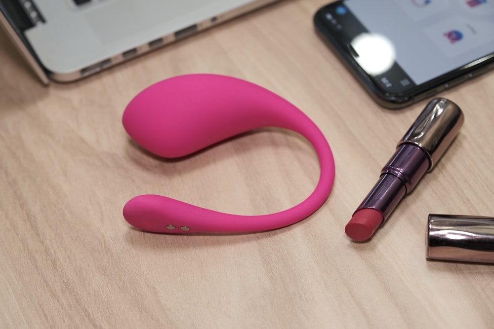 a table with a cell phone, lipstick, and a laptop