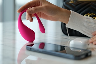 a person holding a pink object near a cell phone