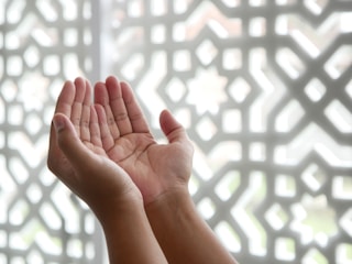 Hands joined together with spiritual symbols in the background.