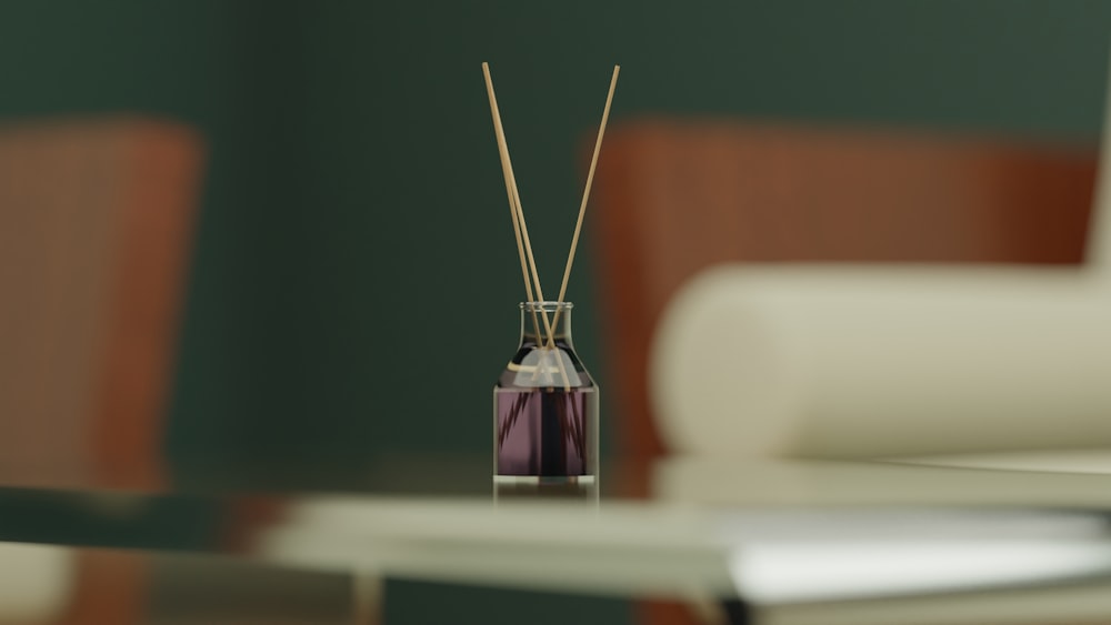 a glass vase with reeds in it sitting on a table