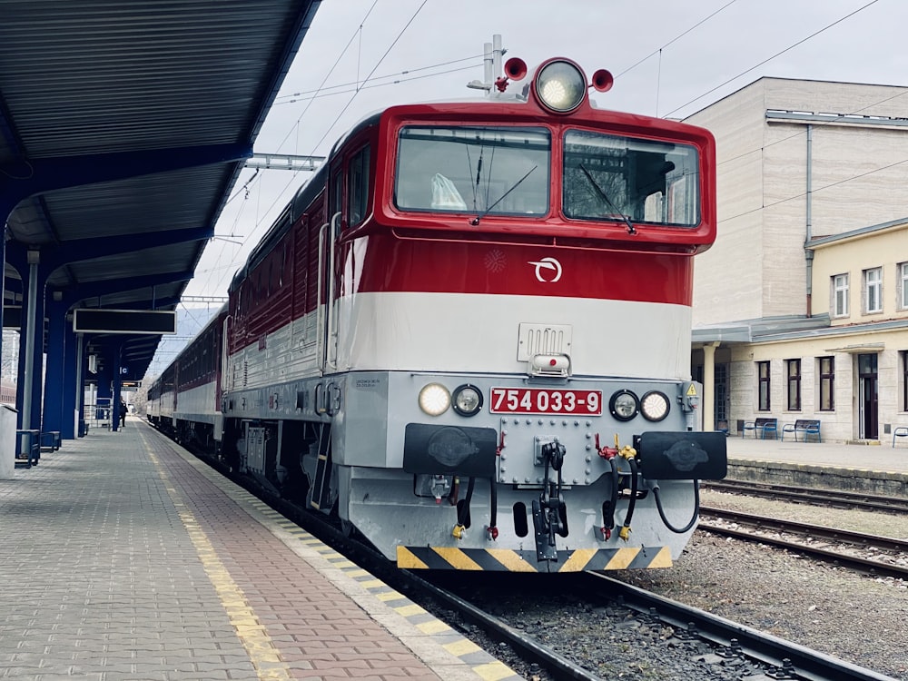 a red and white train pulling into a train station
