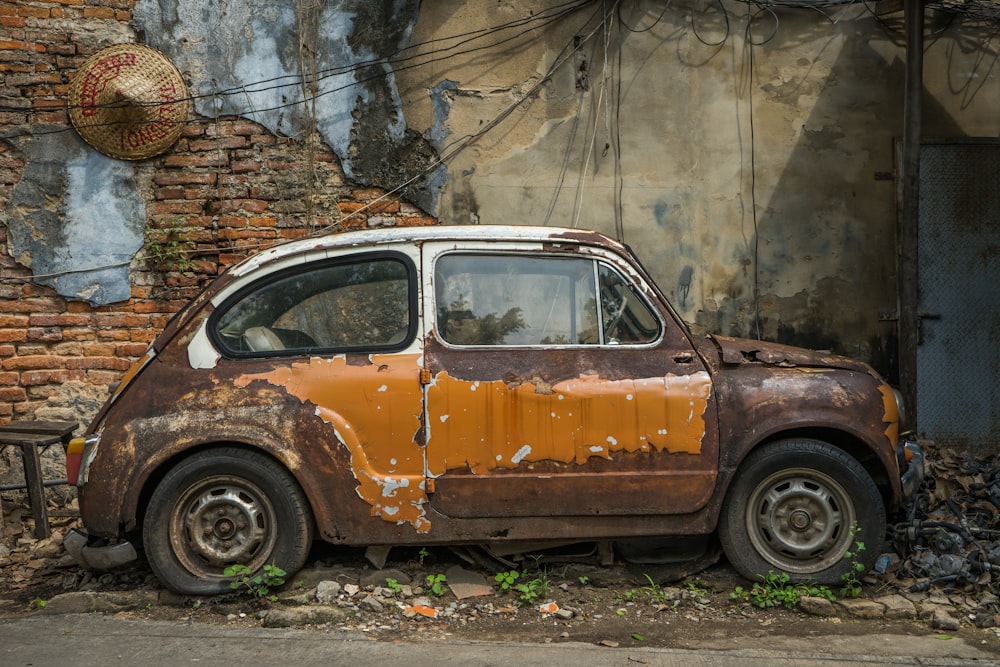 an old rusted car parked in front of a building