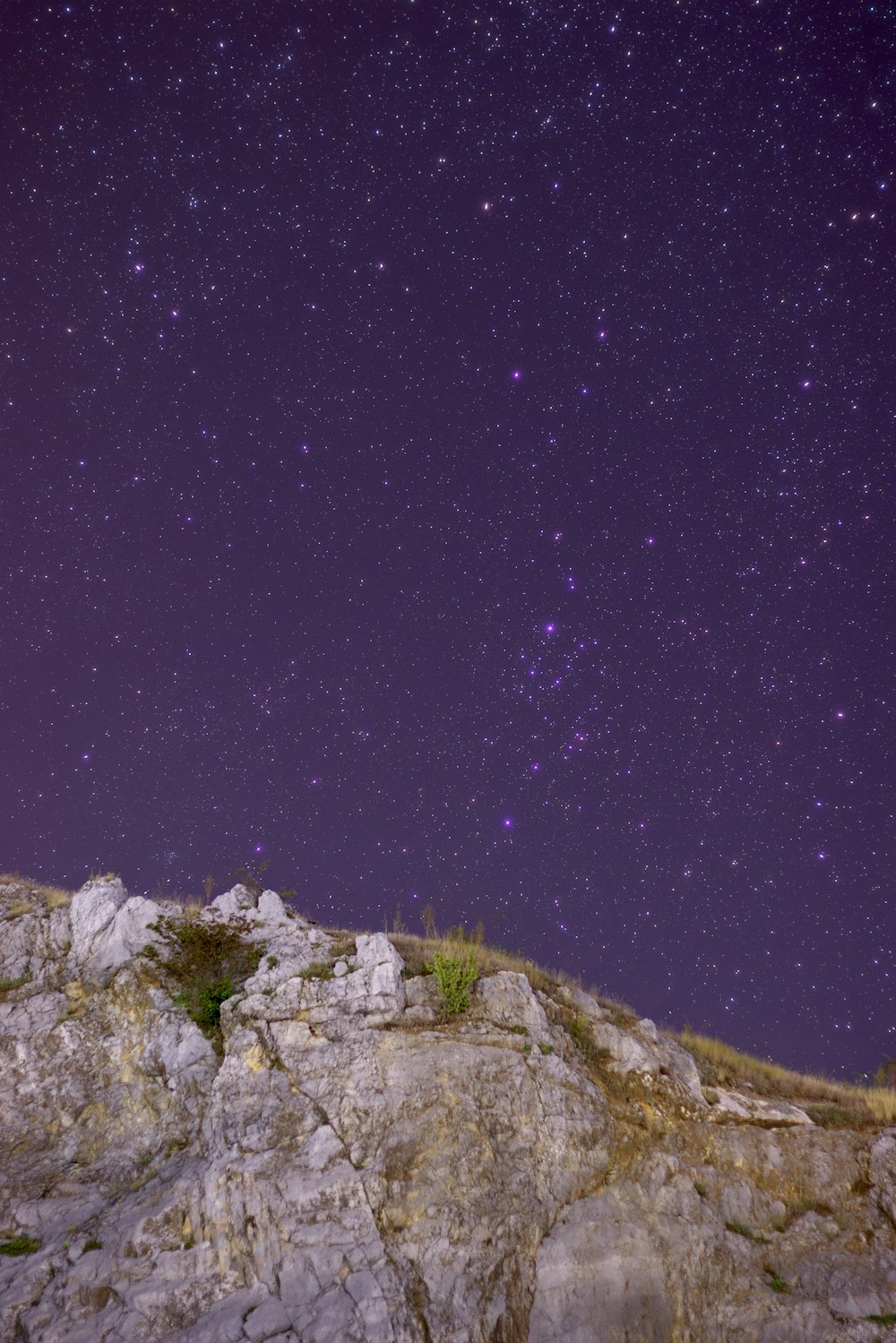 El cielo nocturno está lleno de estrellas sobre una colina rocosa