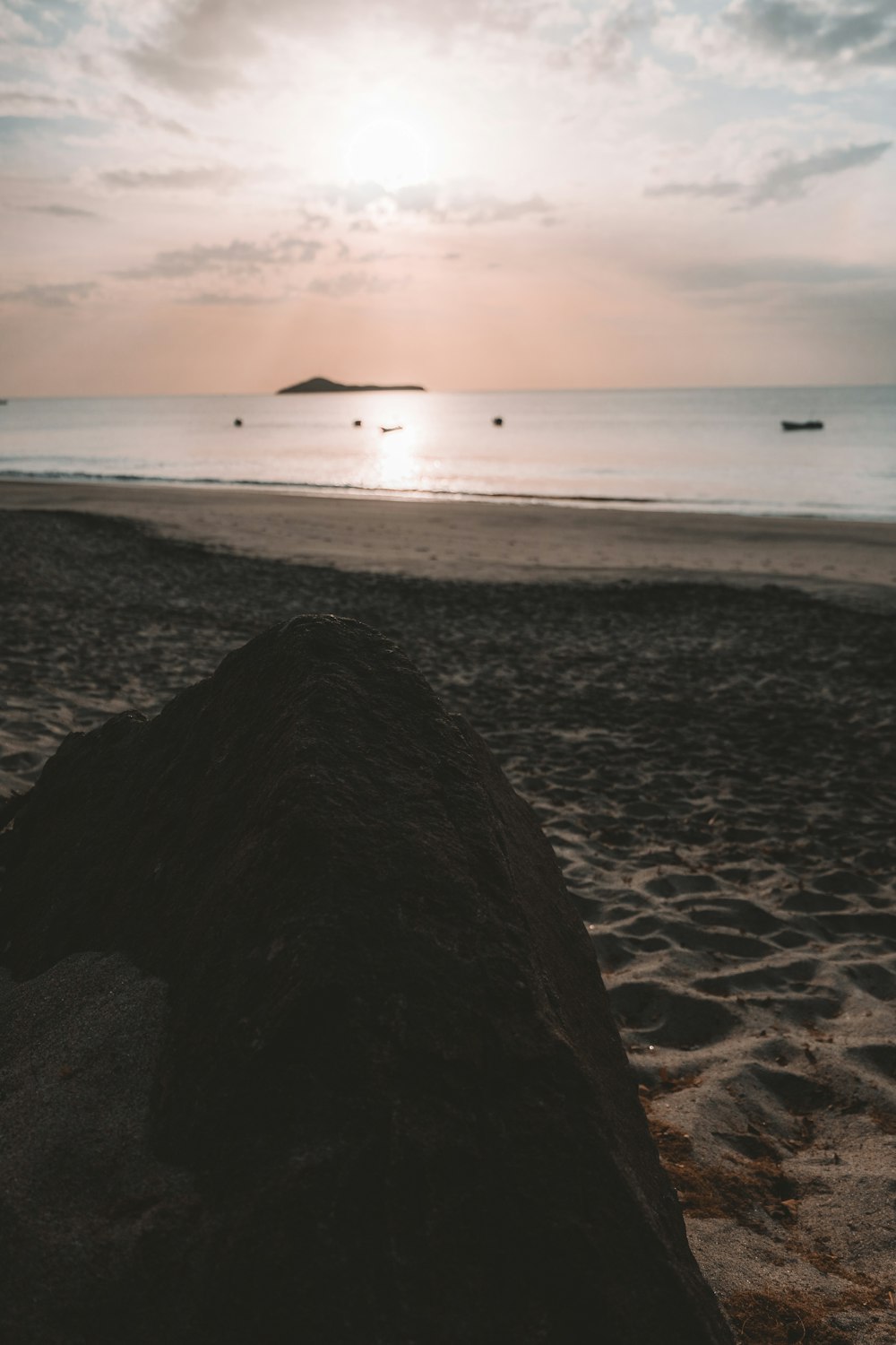 the sun is setting on the beach with a surfboard