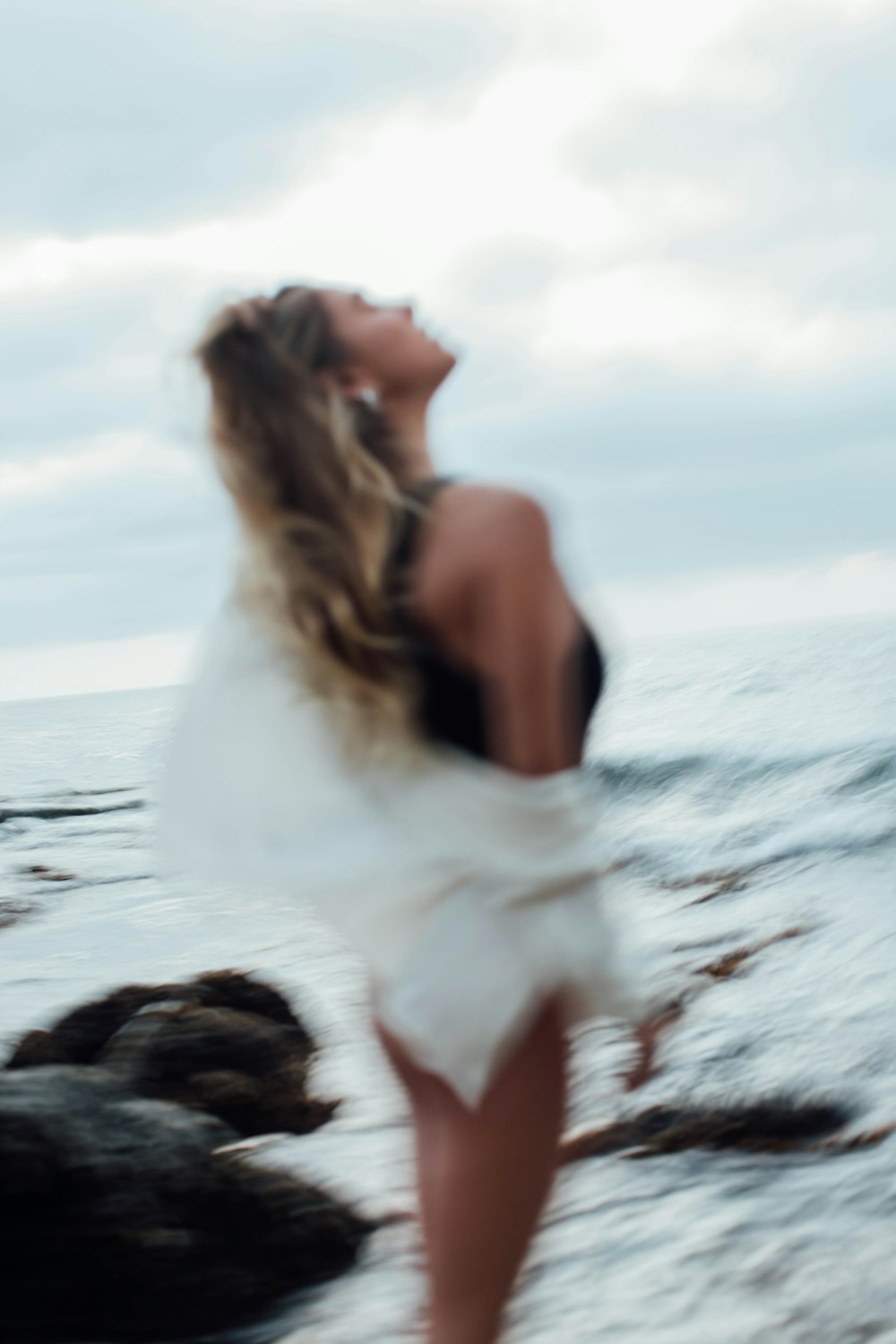 a woman standing on top of a beach next to the ocean