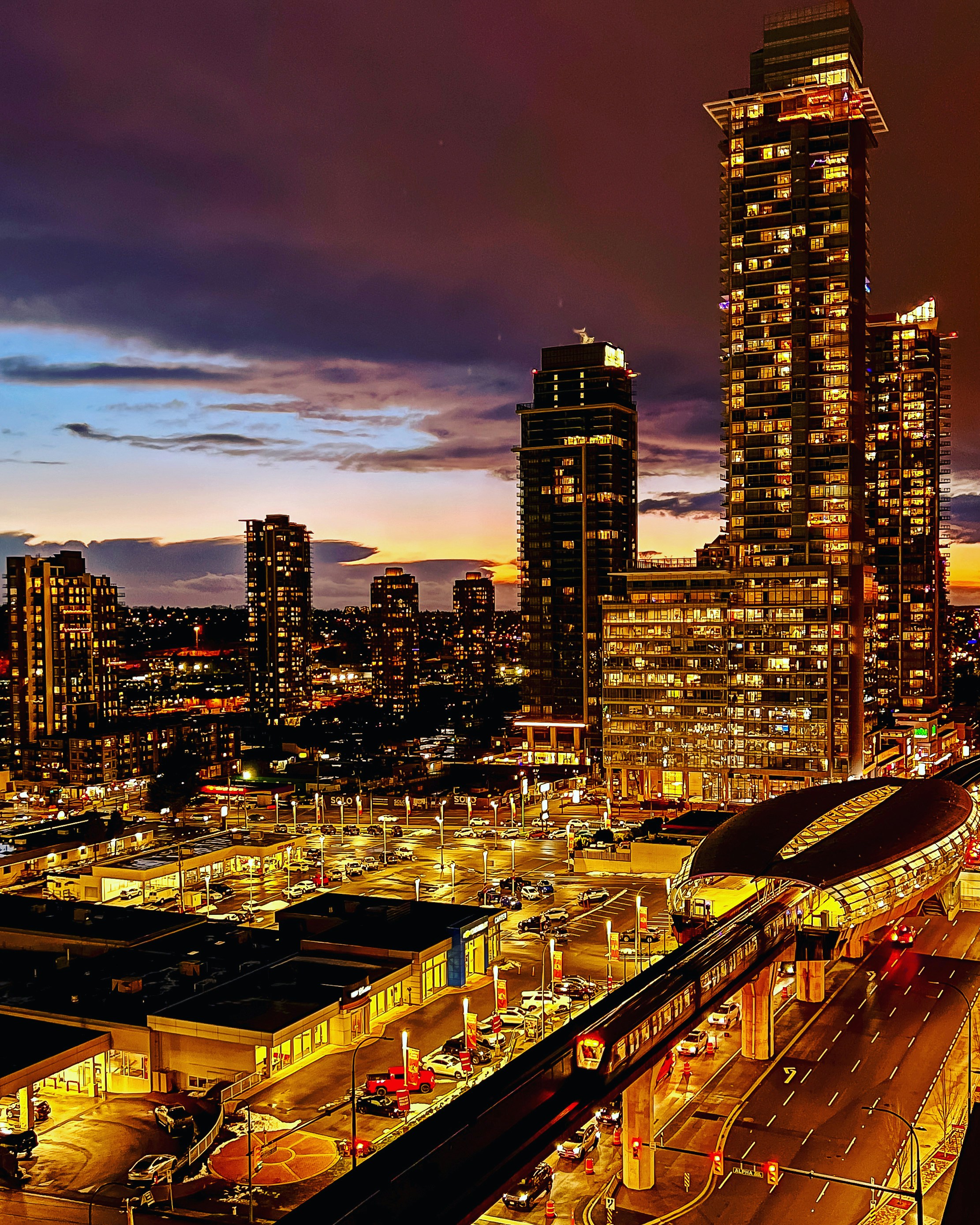 a city skyline at night with a train station in the foreground