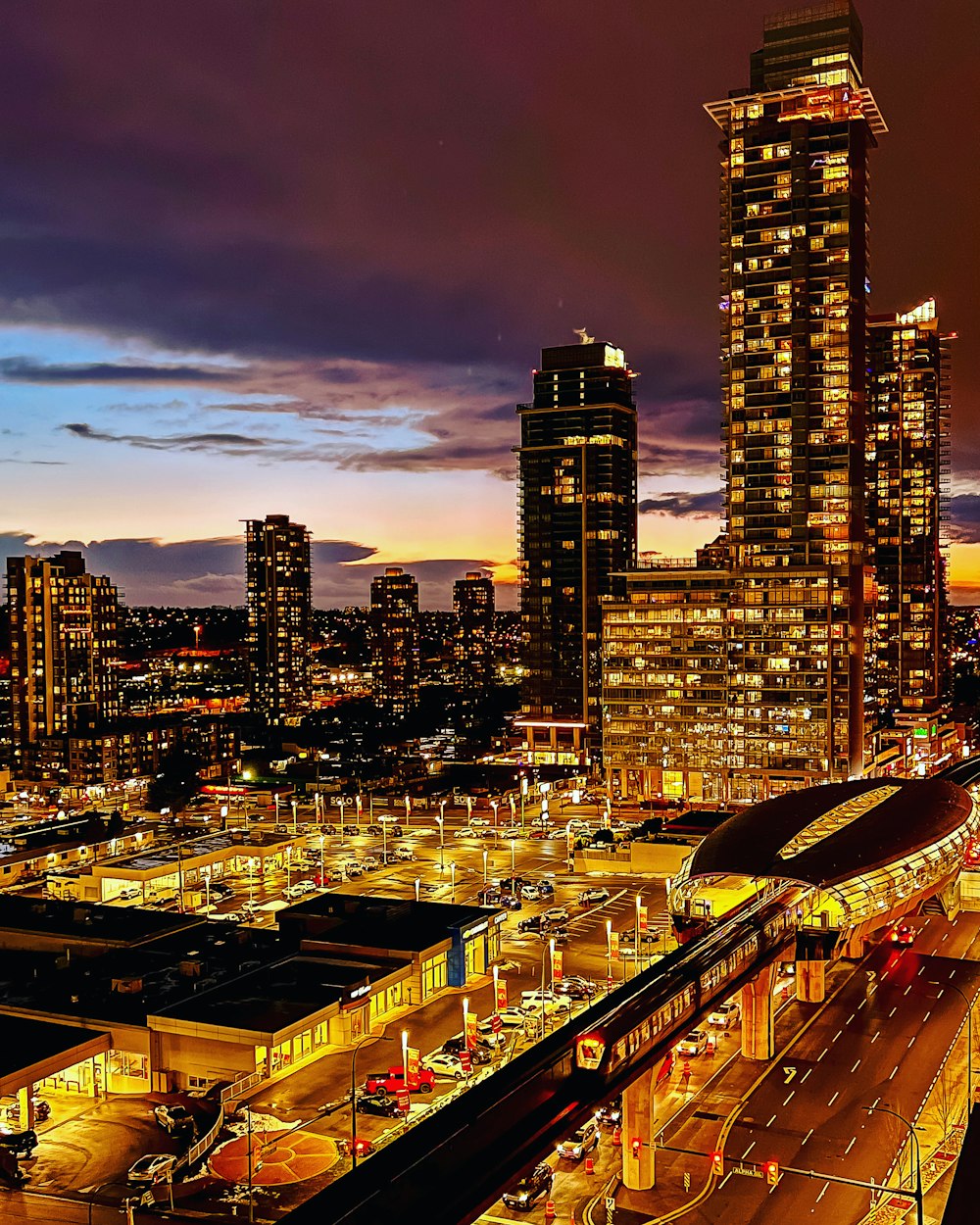 a city skyline at night with a train station in the foreground