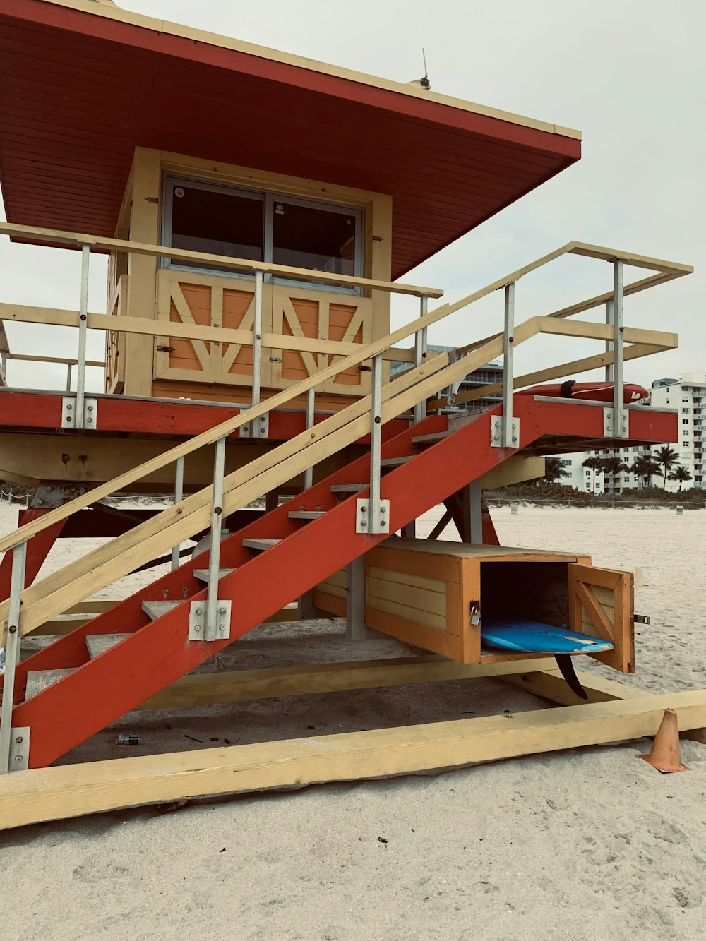 a lifeguard station on the beach with a surfboard under it