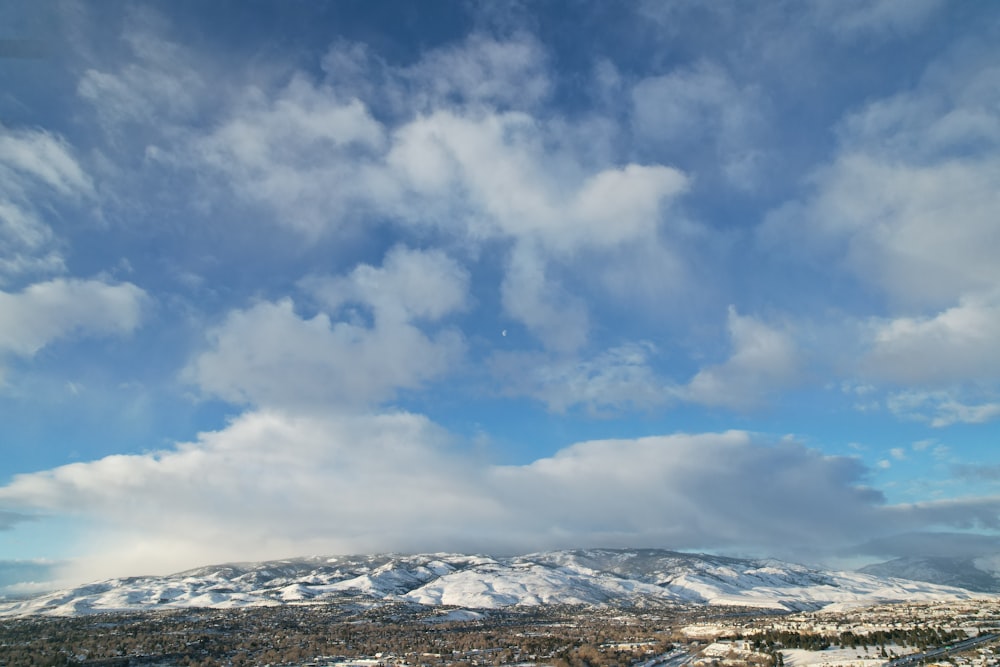 a view of a snow covered mountain with clouds in the sky