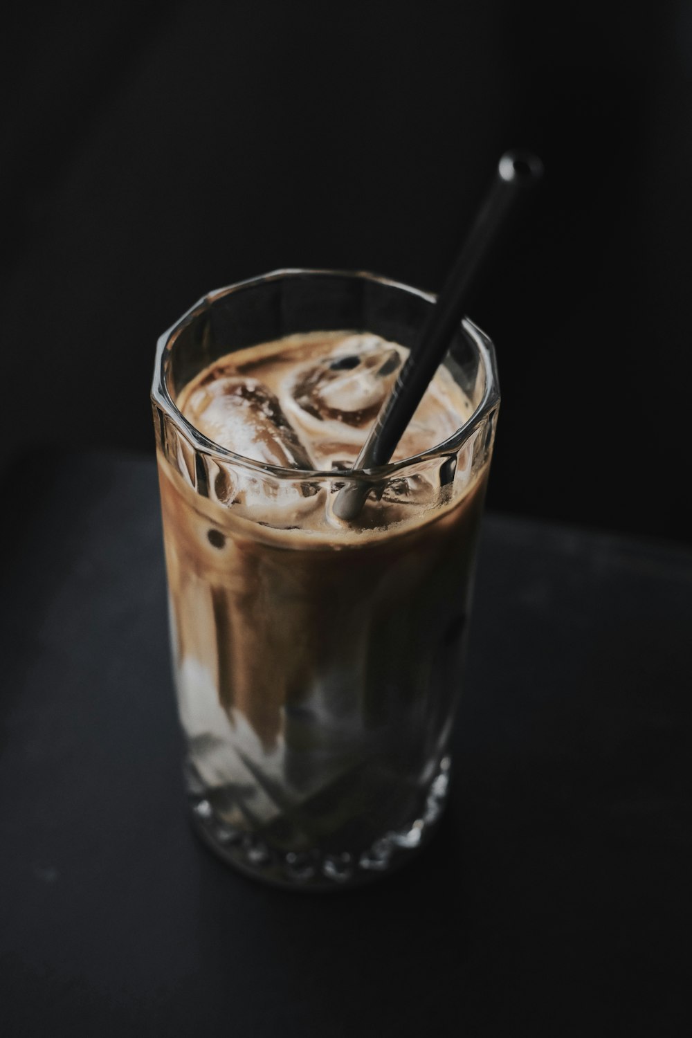 a glass of iced coffee with a spoon in it