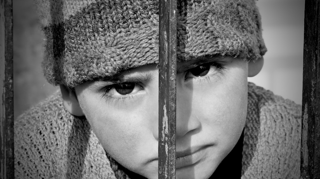 a young boy wearing a hat behind bars,
